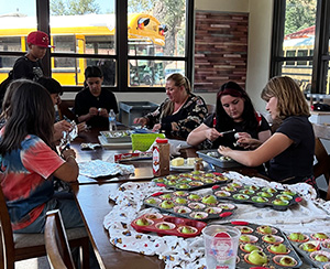 Group of students and adults at a table working on snacks