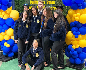 Group of students in blue and gold jackets posing for a picture